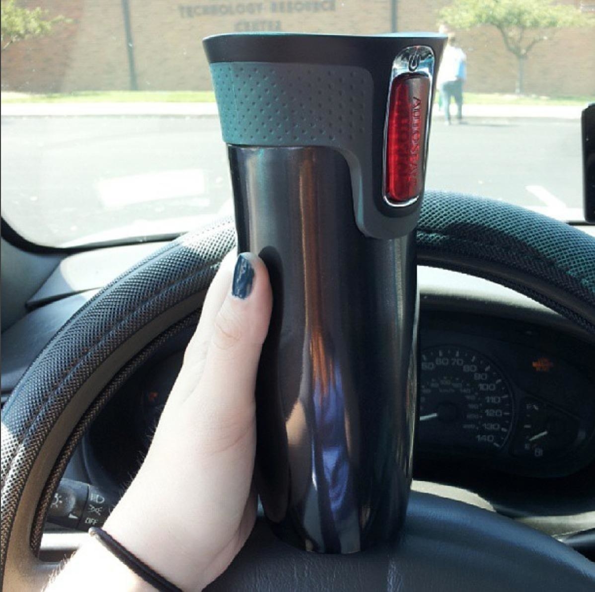 Reviewer holding the travel mug up in car
