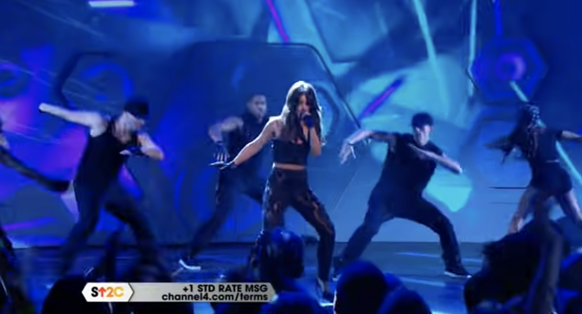 Cheryl performing on stage with dancers