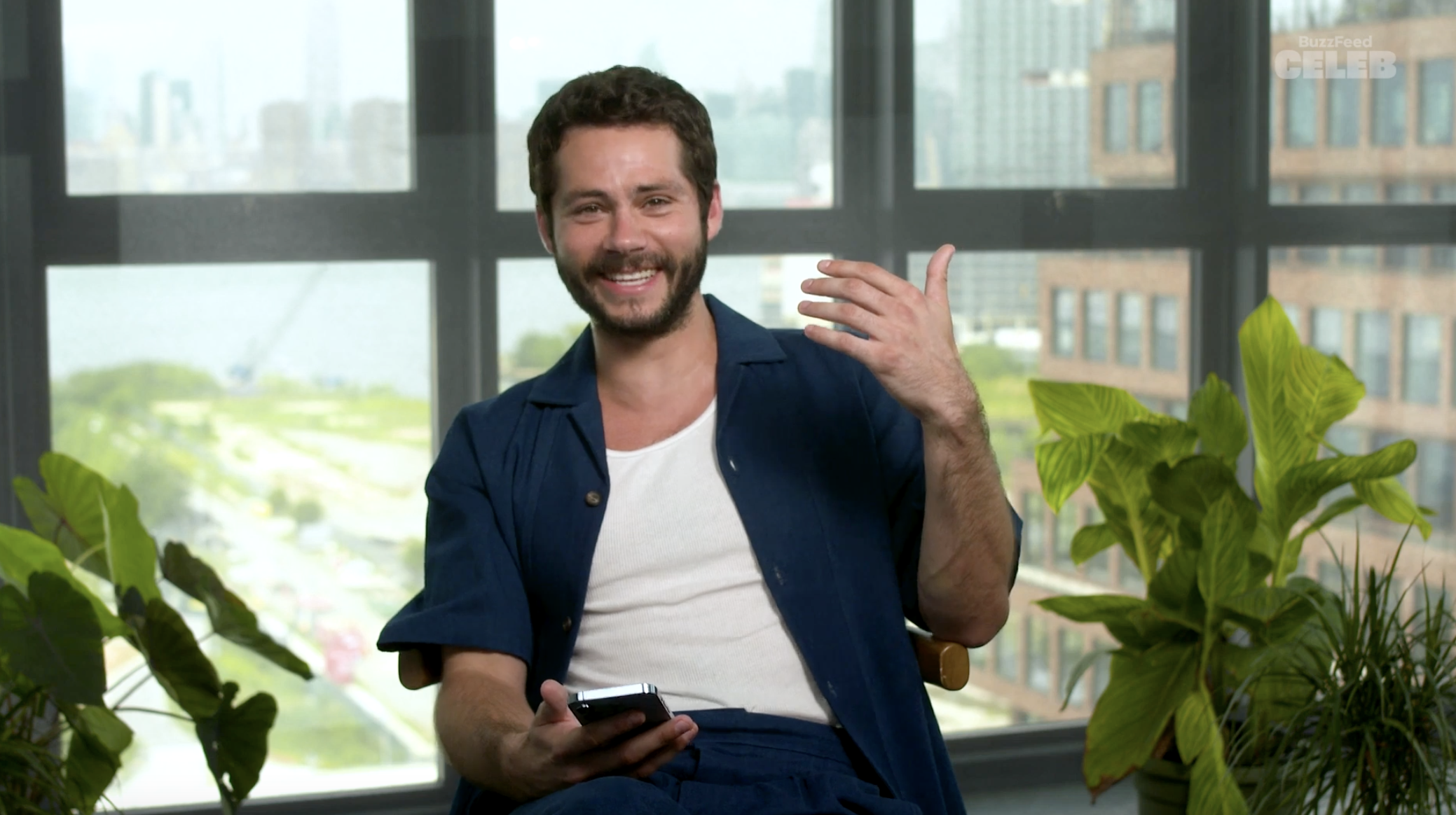 Dylan holding a cellphone as he sits in front of a window