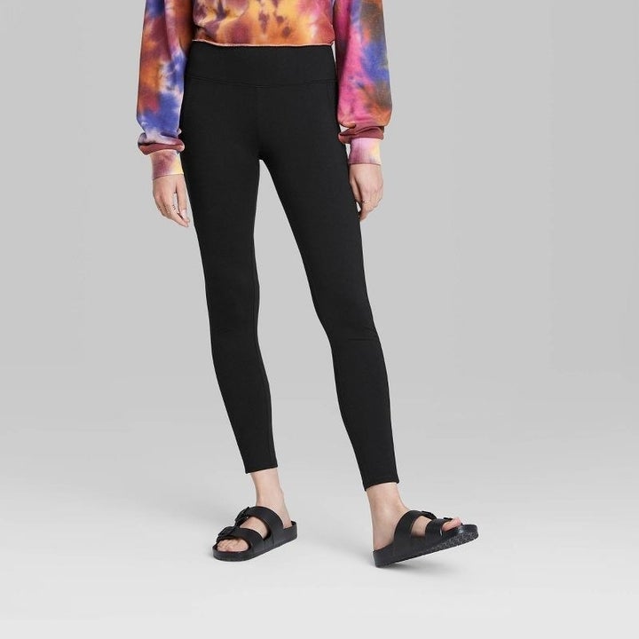 A model wearing black leggings, black sandals and a red, orange and purple tie dye shirt
