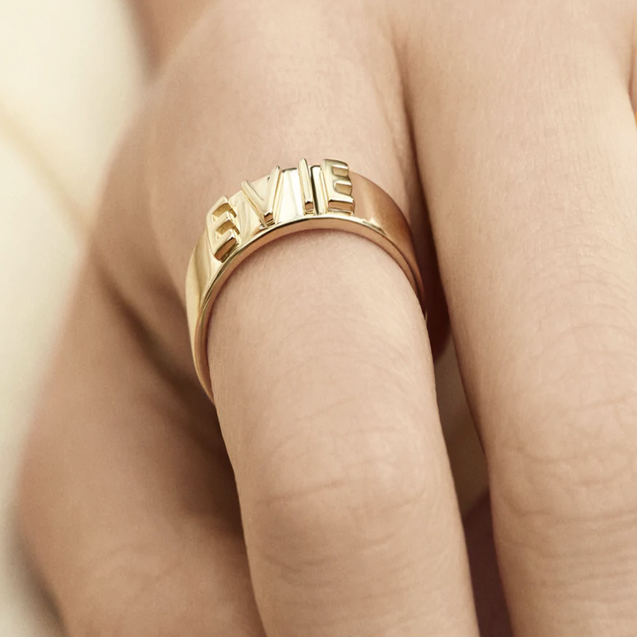 14K gold ring with raised-block font that says "evie"