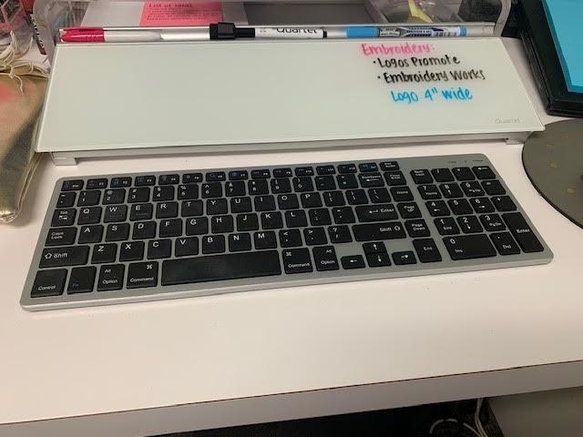 the white board between a computer keyboard and monitor on a decorated desk