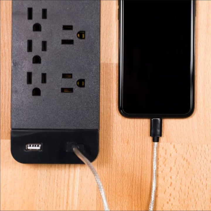 the end of the black surge protector being used to charge a phone