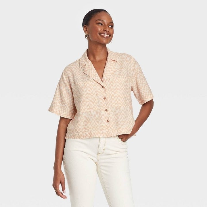 A model wearing a white and tan checkered top with white jeans