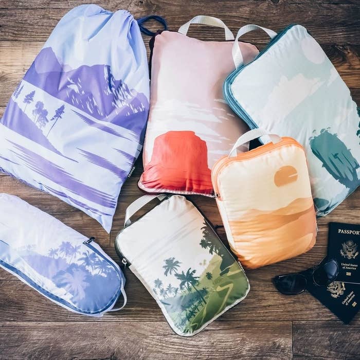 a flatlay of the compressive packing cubes arranged on a floor next to some passports