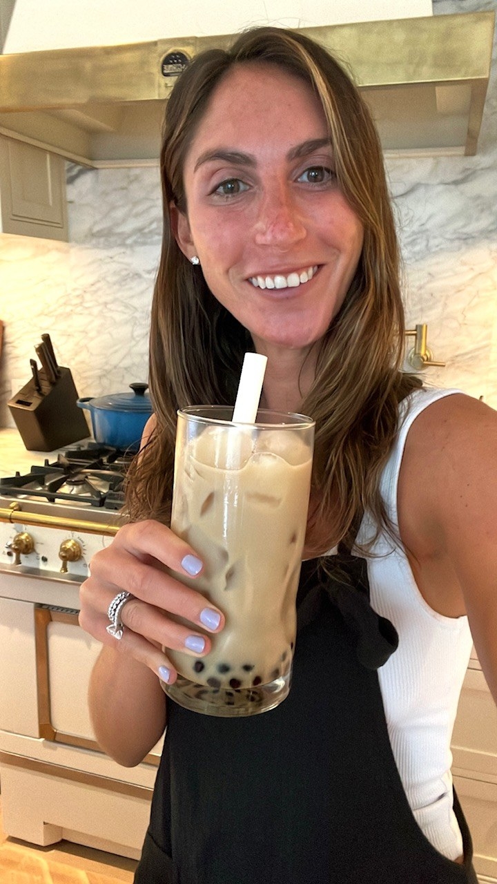 A woman smiling holding a glass of boba tea.