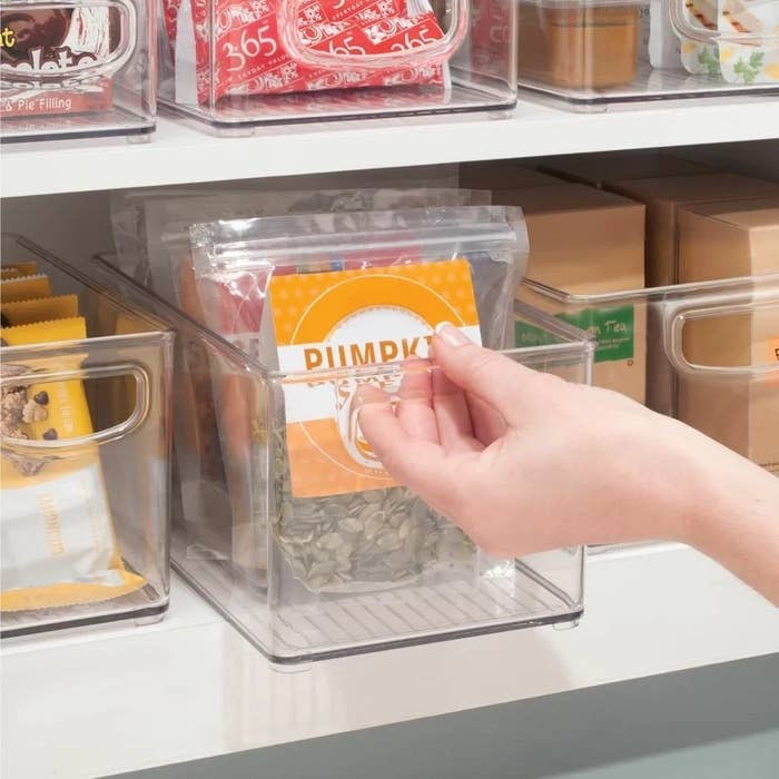 A person reaches for snacks in the clear plastic organizer