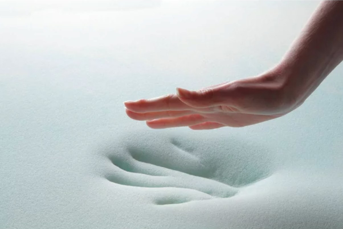 a model&#x27;s hand pressing an imprint into the blue memory foam