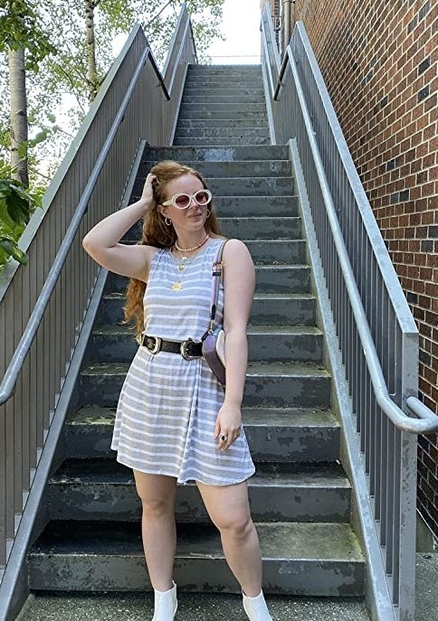 A person wearing the dress by some stairs outside with a belt and boots