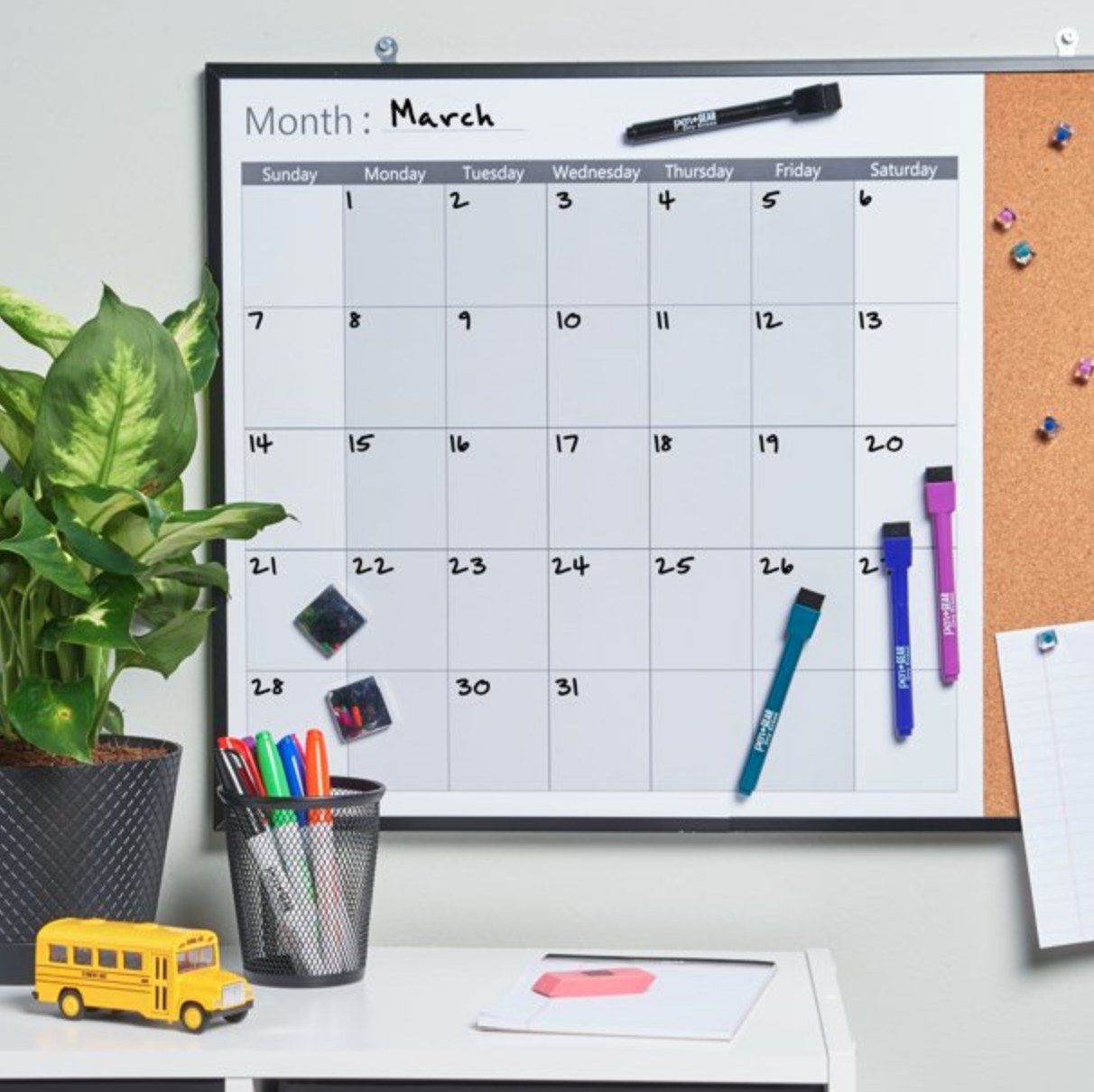 the calendar on a wall above a decorated desk space