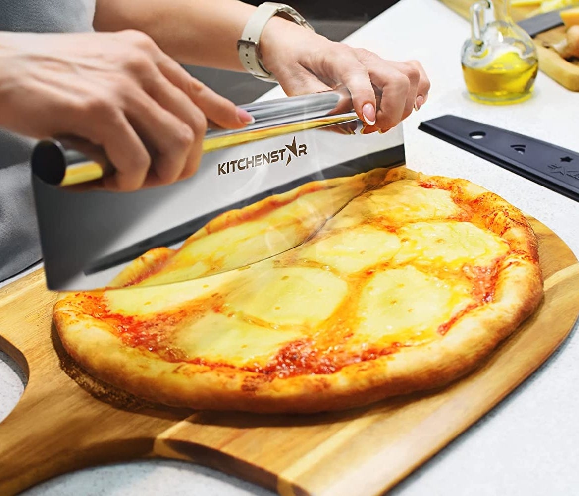 A person using the cutter to slice a pizza