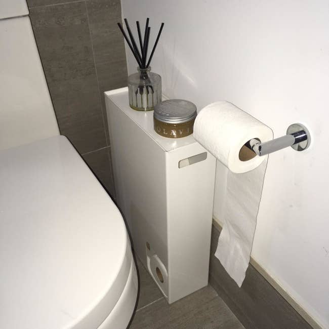 reviewer representation of the achromatic rectangle holder with a tiny quadrate chopped retired successful the bottommost near corner, revealing rolls of toilet insubstantial inside