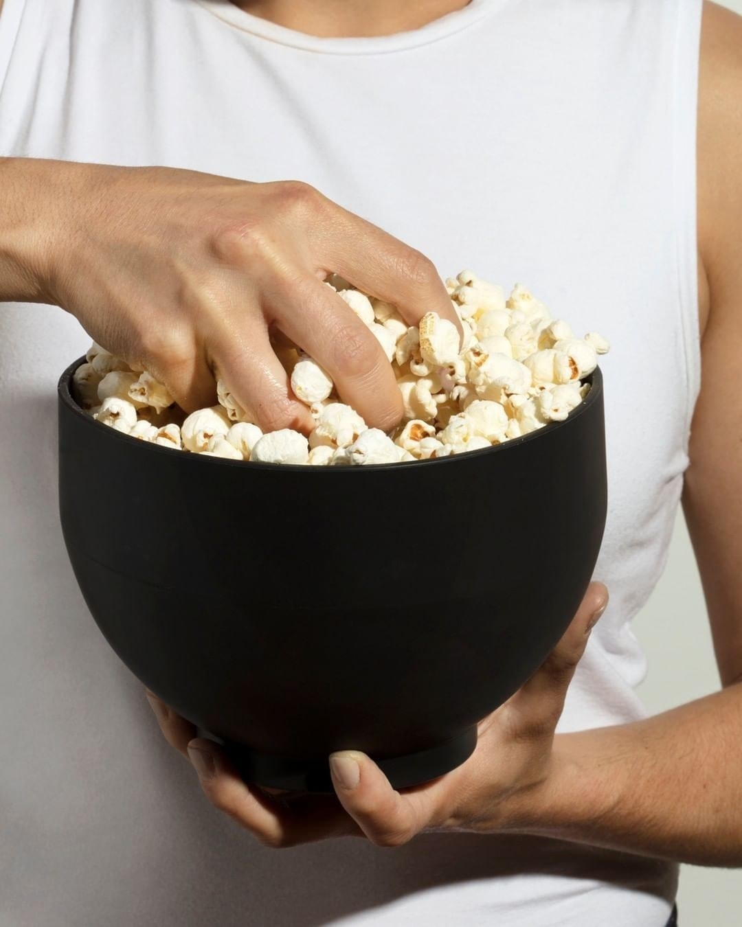 someone grabbing a fistful of popcorn out of the collapsible bowl