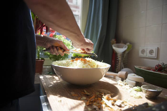 A man cooking in a messy workspace.