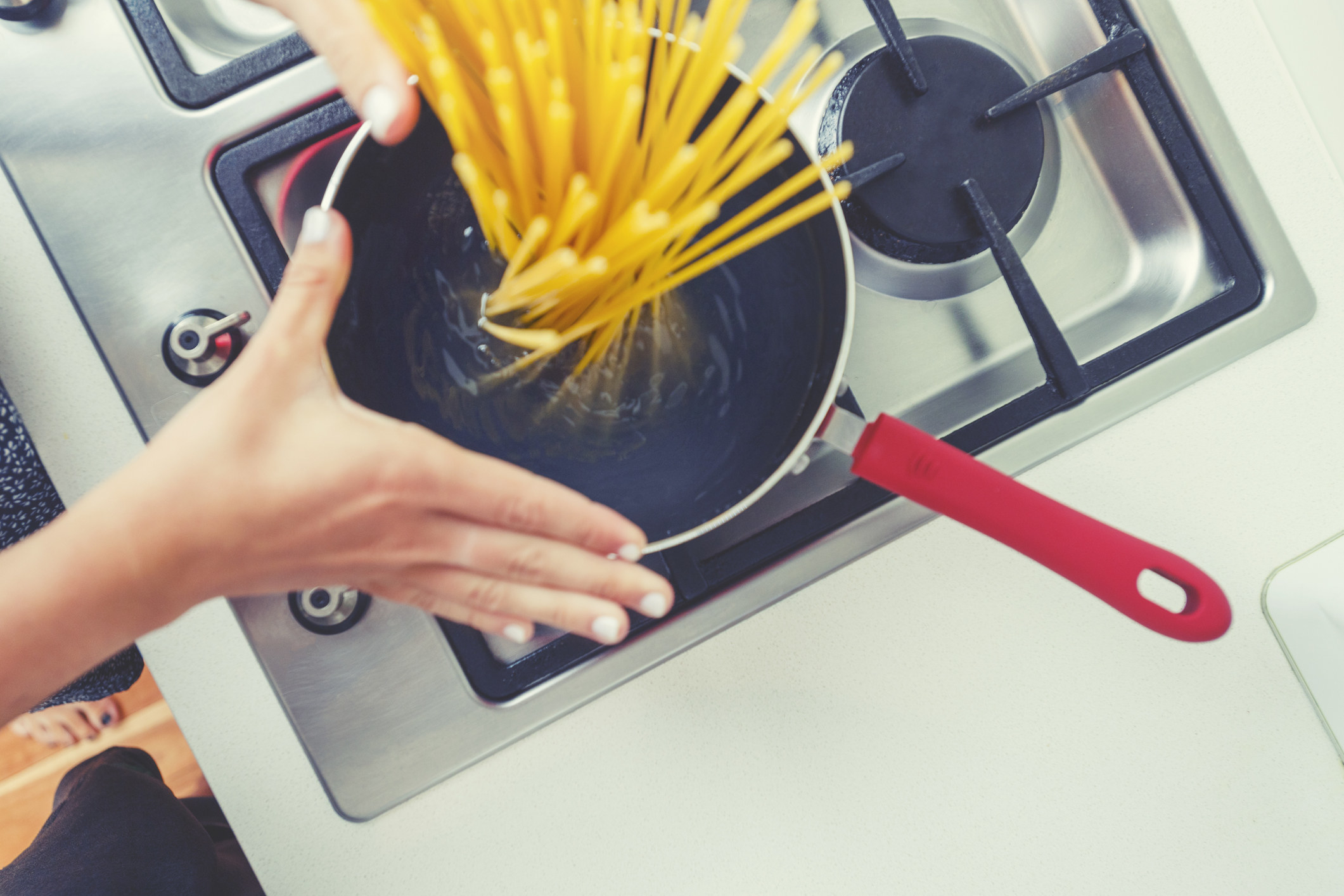 Woman dropping pasta into boiling water.