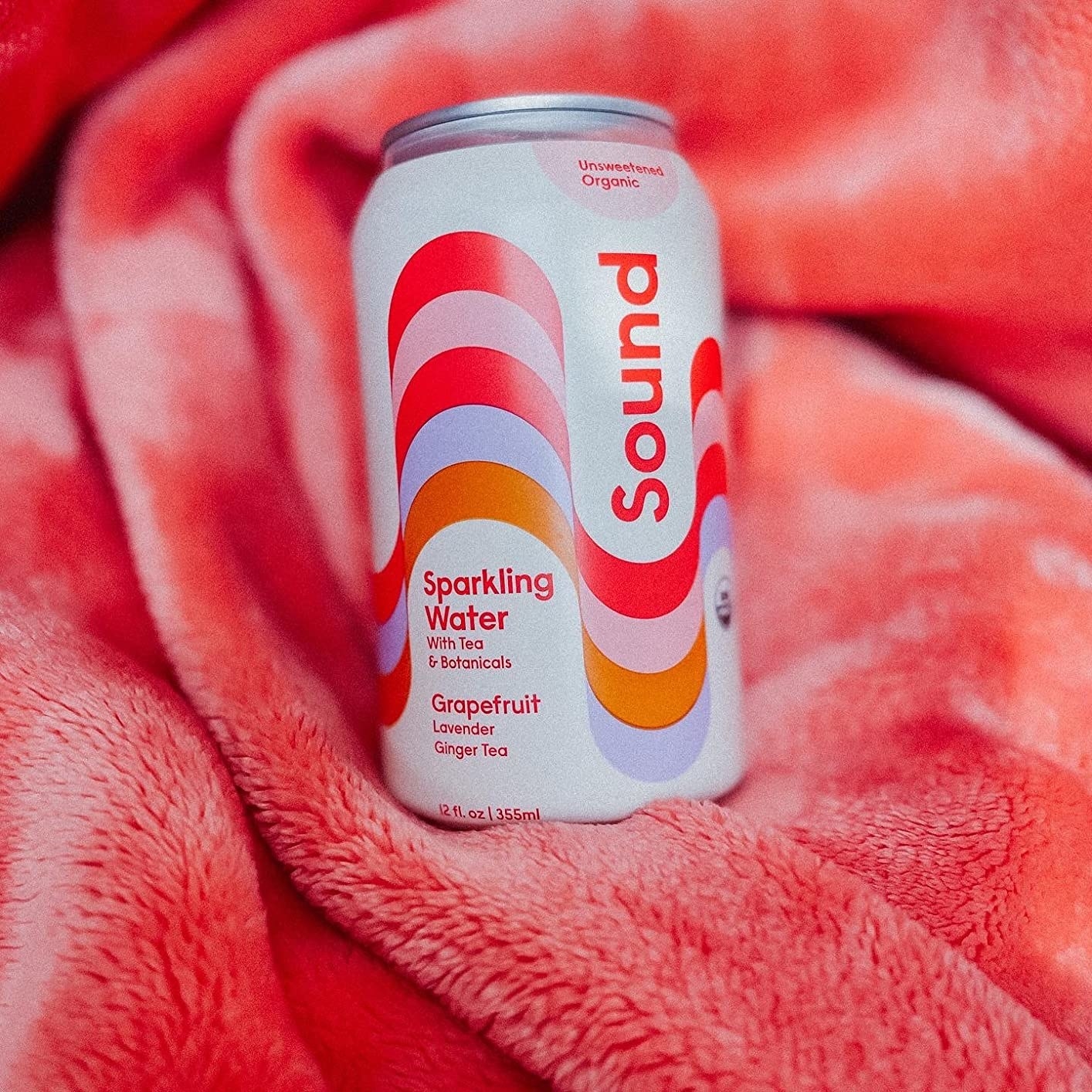 a can of sparkling water with colorful wave design on it