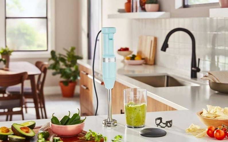 Immersion blender on counter next to container with blended avocado