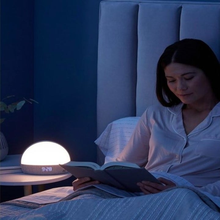 Model reading in bed at night with the Hatch lit up on a nightstand