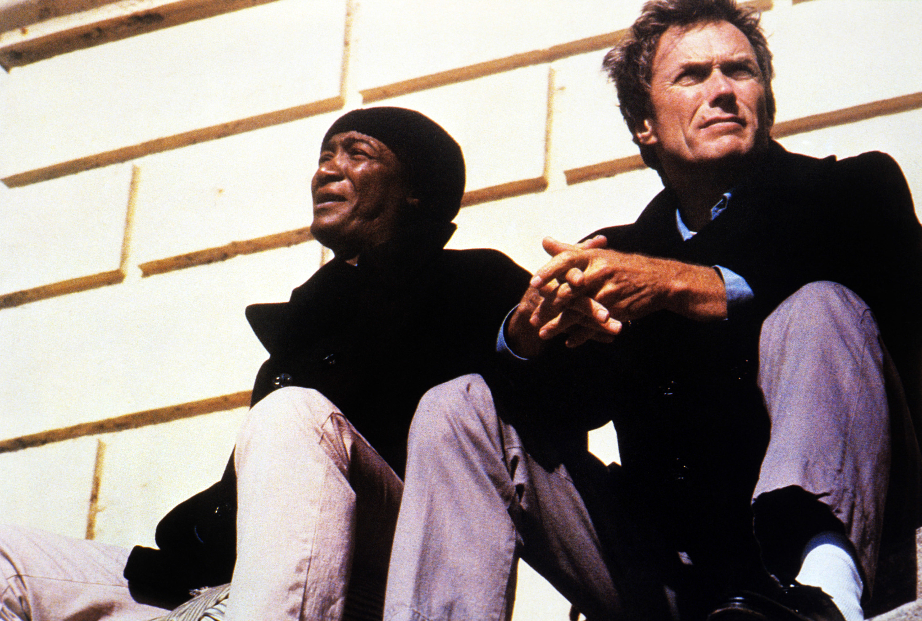 Paul Benjamin and Clint Eastwood sit outside a building