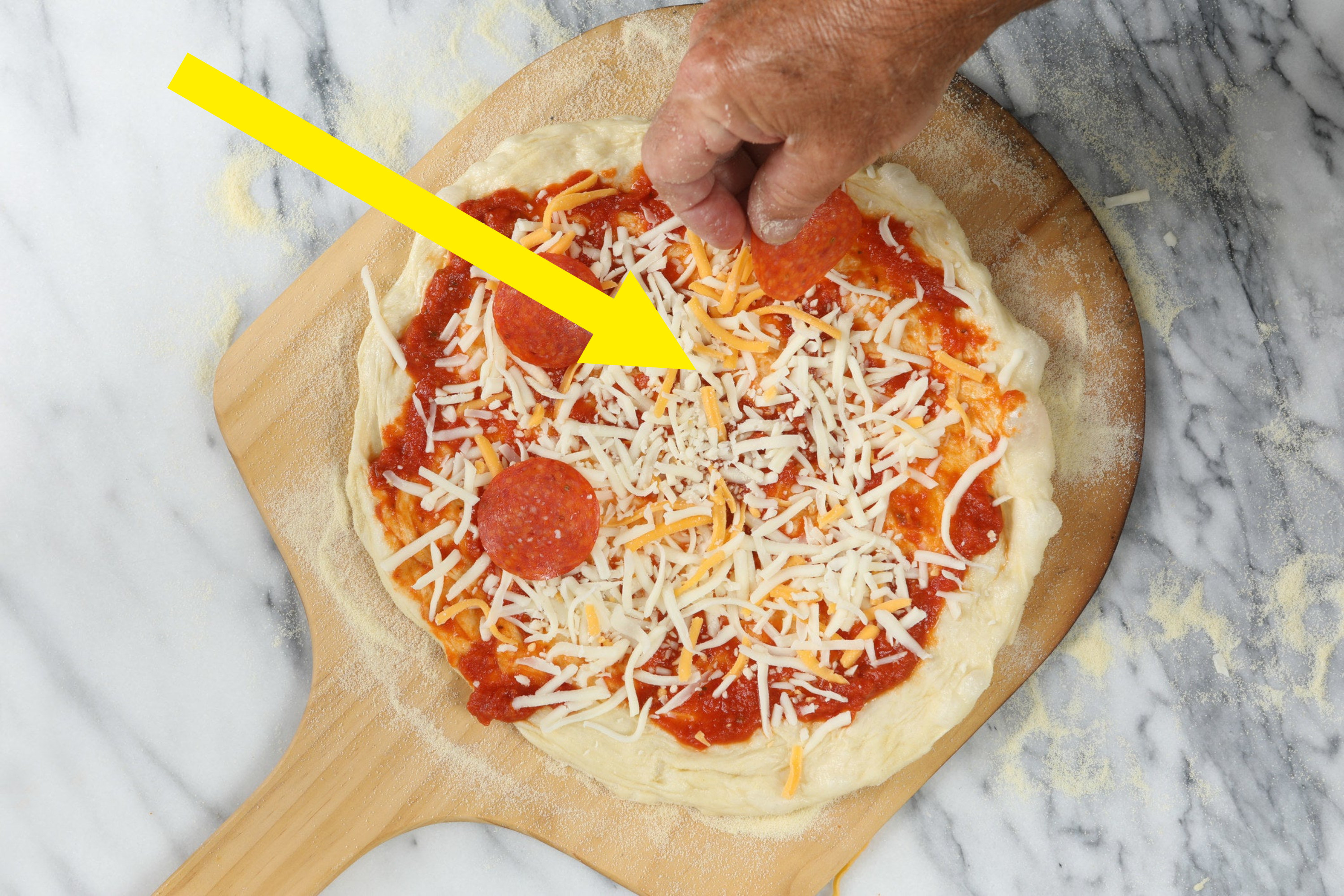 A person preparing pepperoni pizza.