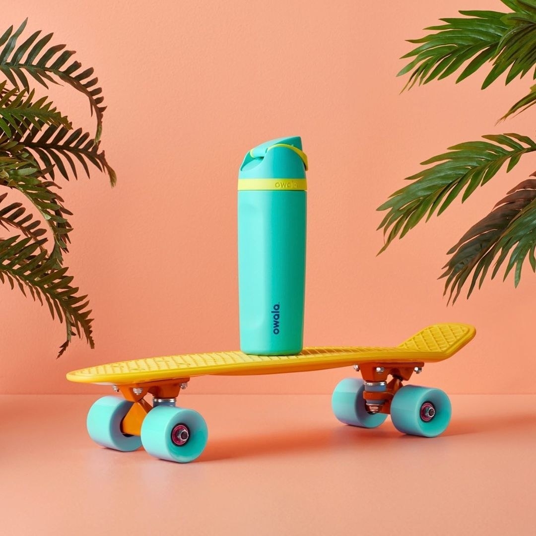 The teal water bottle on a small skateboard