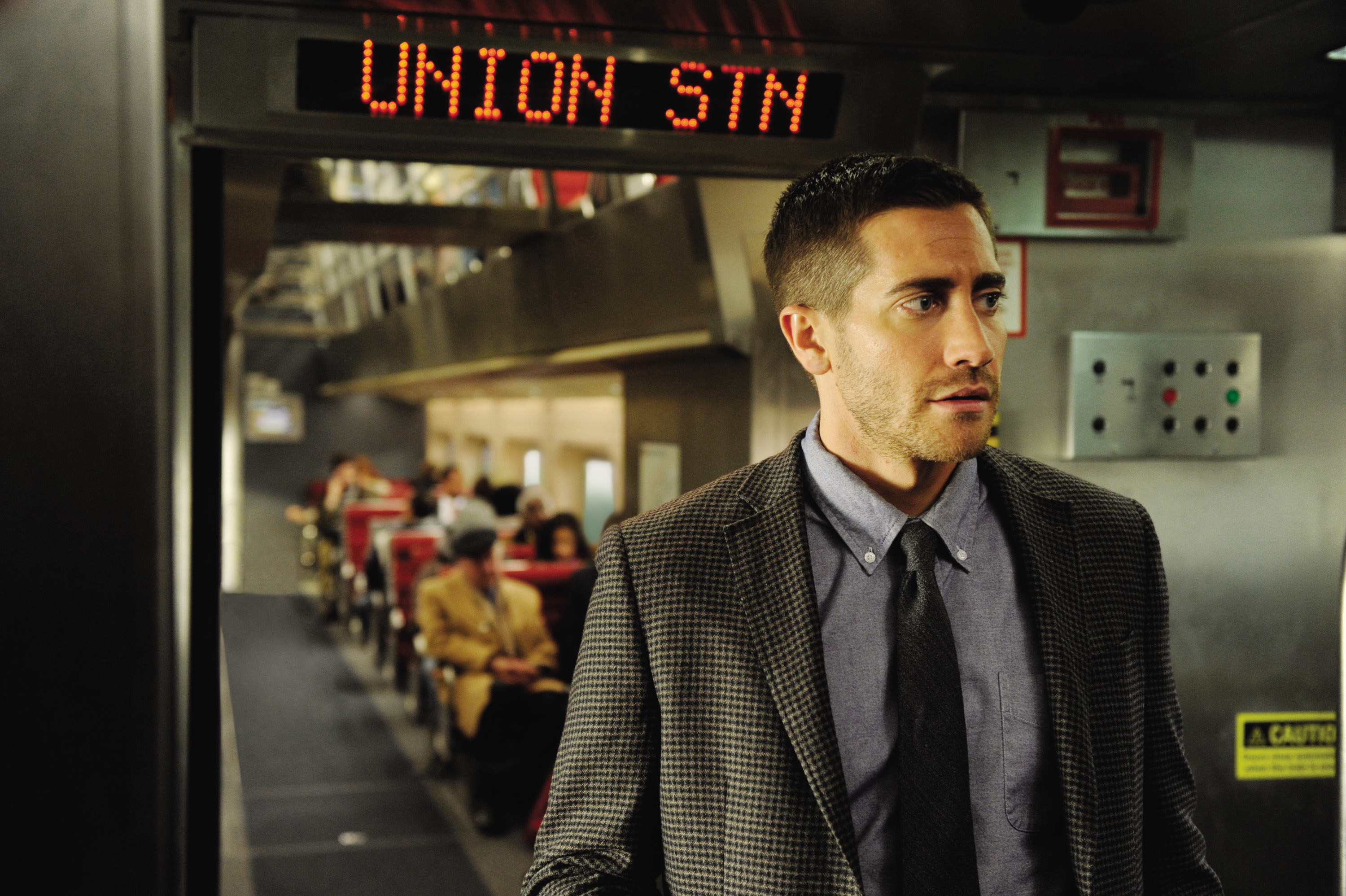 Jake Gyllenhaal stands in a train aisle