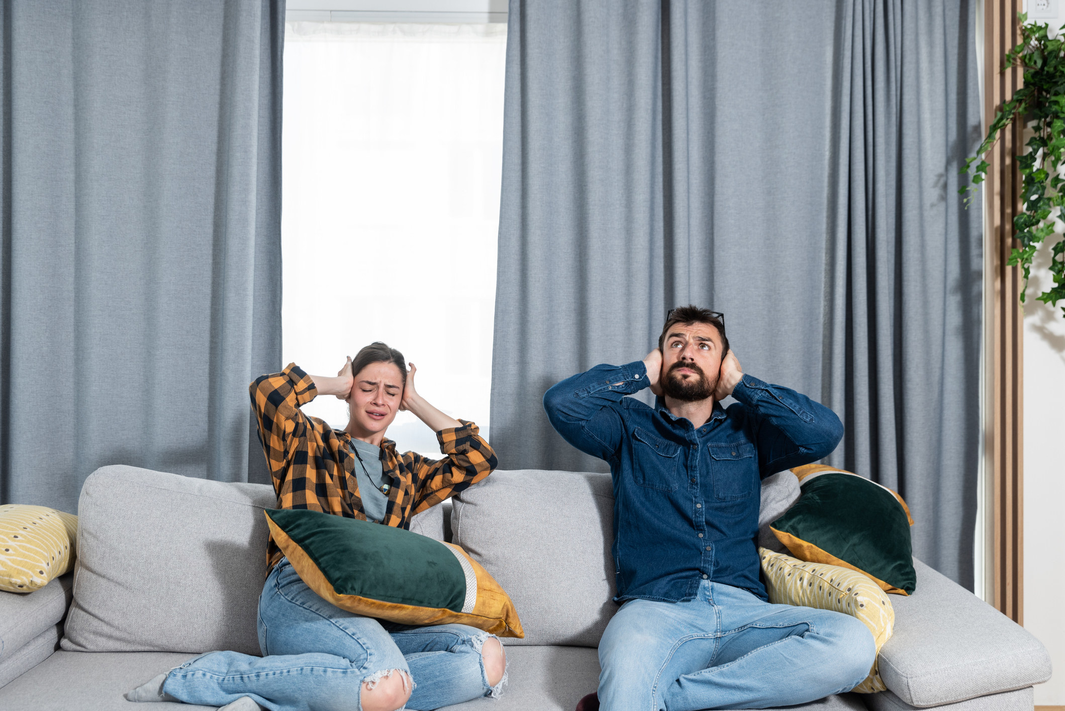 couple on the couch covering their ears