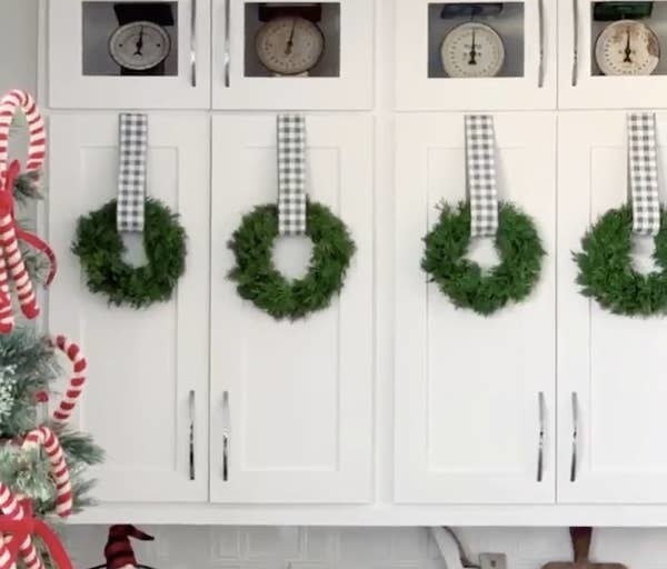 Four small wreaths hanging from kitchen cupboards