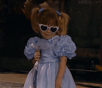 Michelle Tanner in heart shaped sunglasses and wearing a blue puffy sleeve dress doing the happy dance