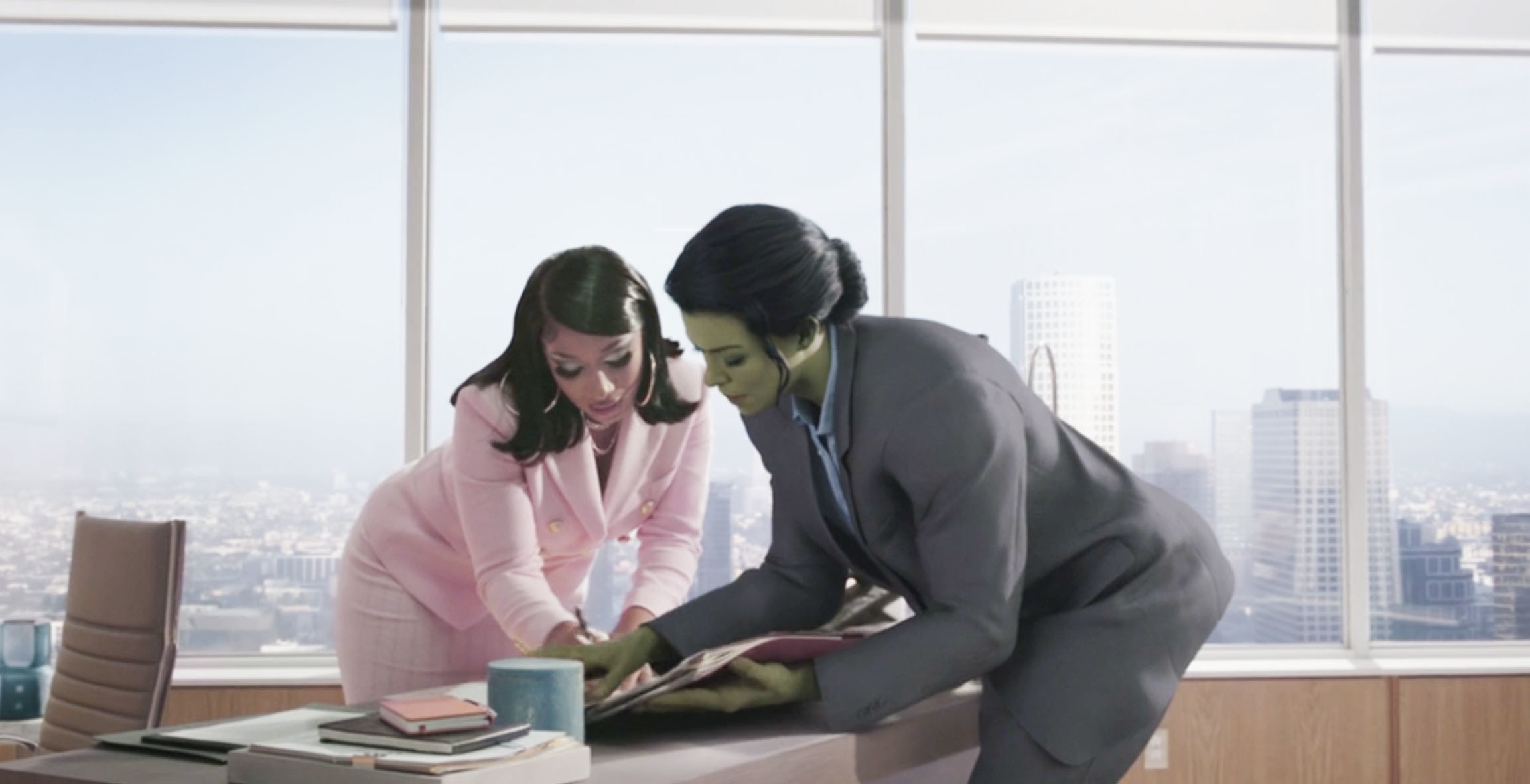 Megan and She-Hulk looking at something on a desk