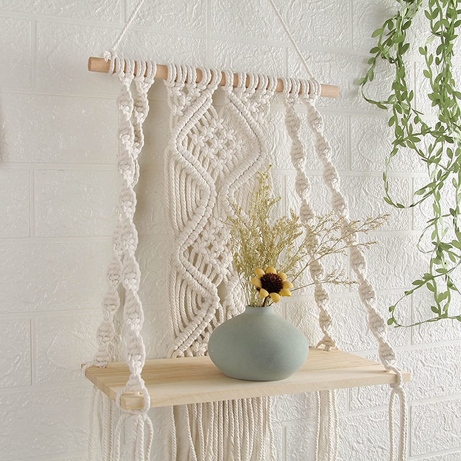 a macrame shelf on a wall holding a vase full of flowers