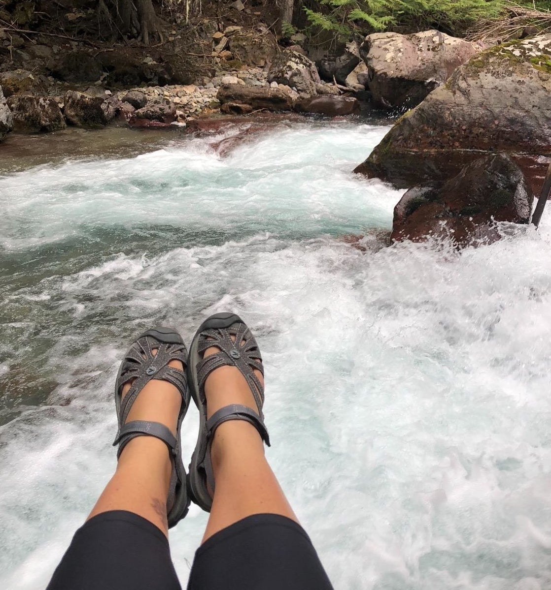 reviewer wearing the sandals to hike next to a waterfall
