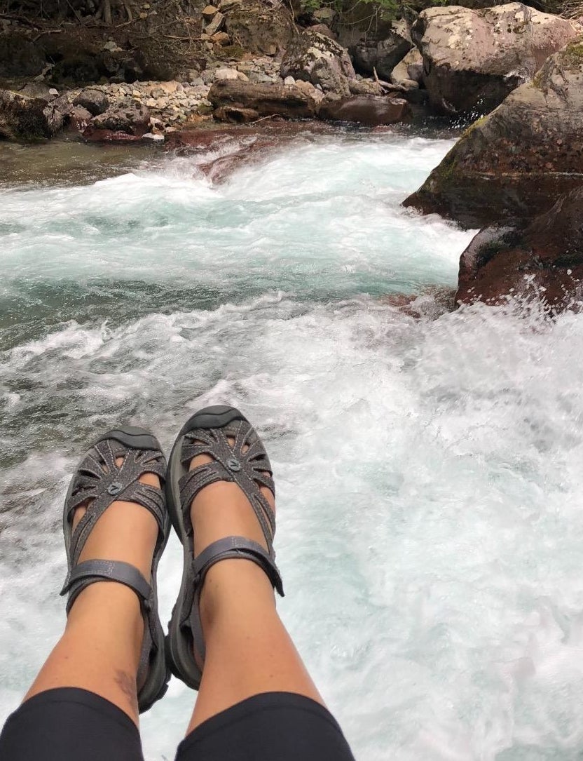 reviewer wearing the sandals to hike next to a waterfall