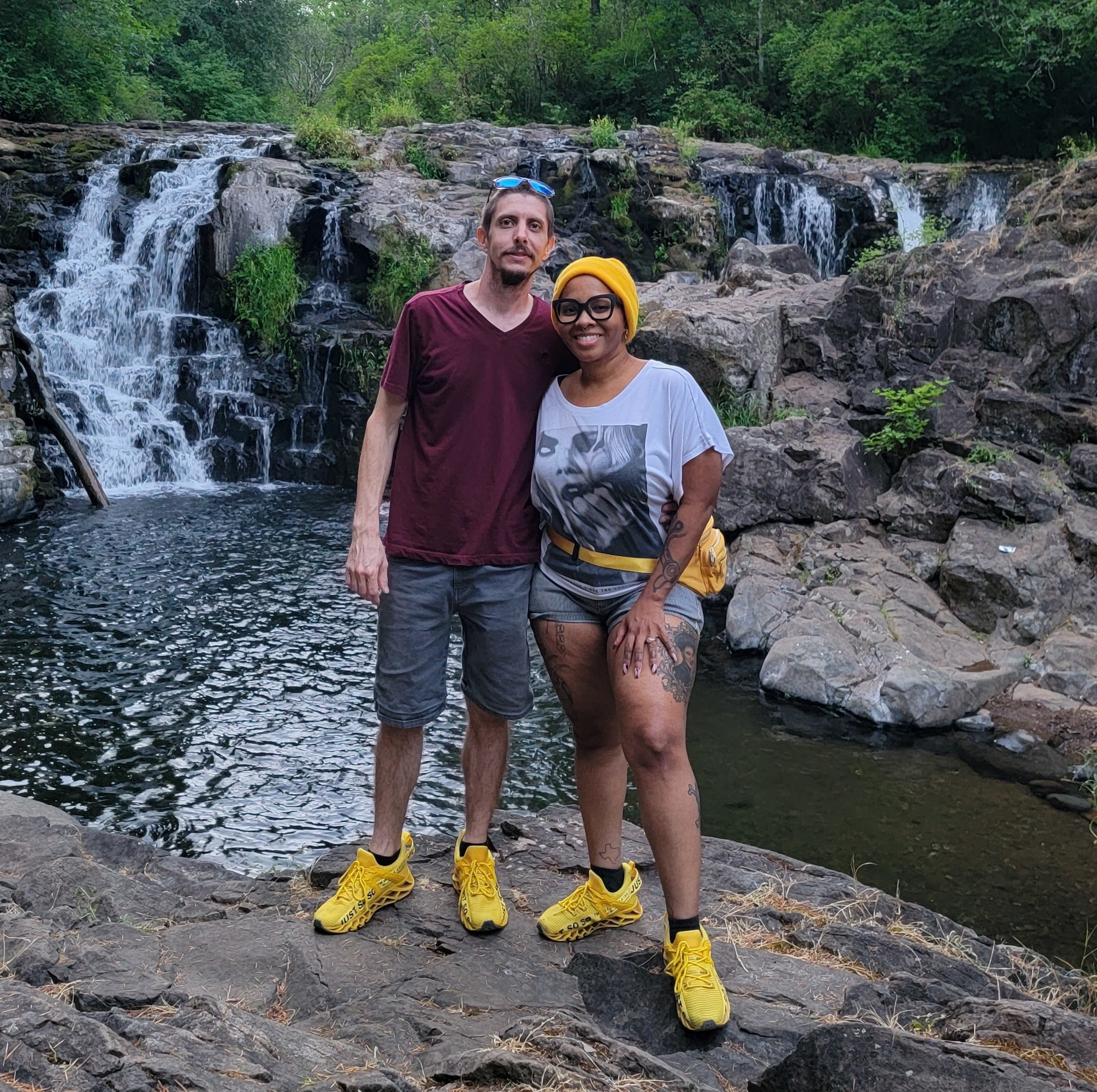 Two reviewers wearing the yellow sneakers in front of waterfall
