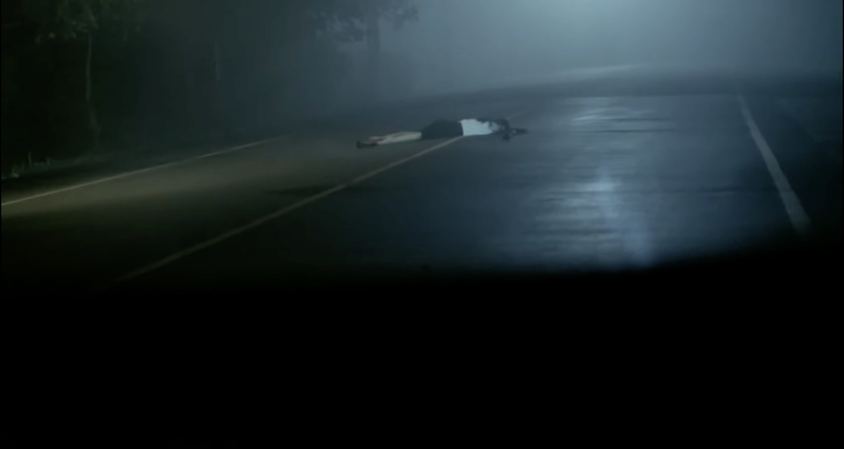A person lying on a dark highway