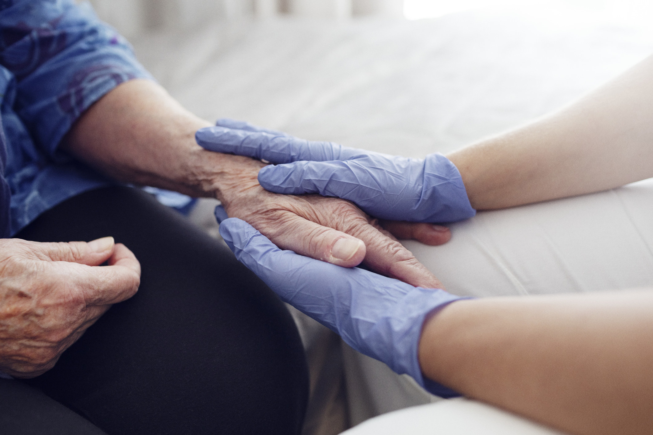 A healthcare worker holding the hand of an older person