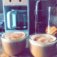 a coffee station with the black milk frother and two lattes