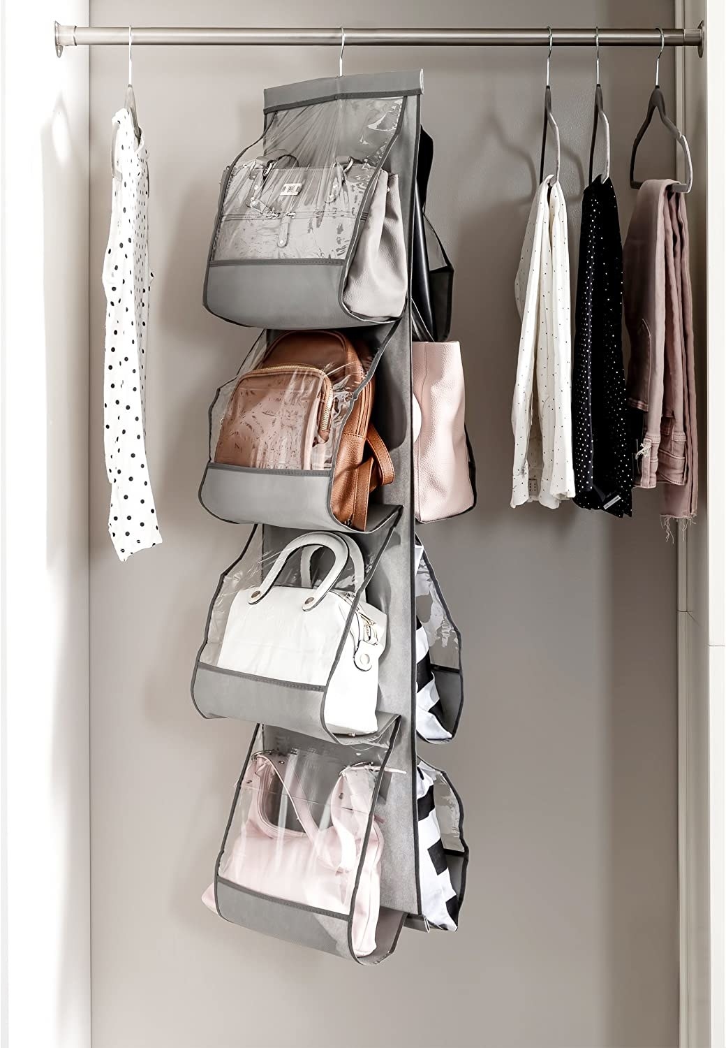 The purse organizer hanging in a closet with purses in it