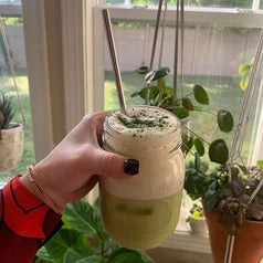 reviewer holding a mason jar drink made with the milk frother