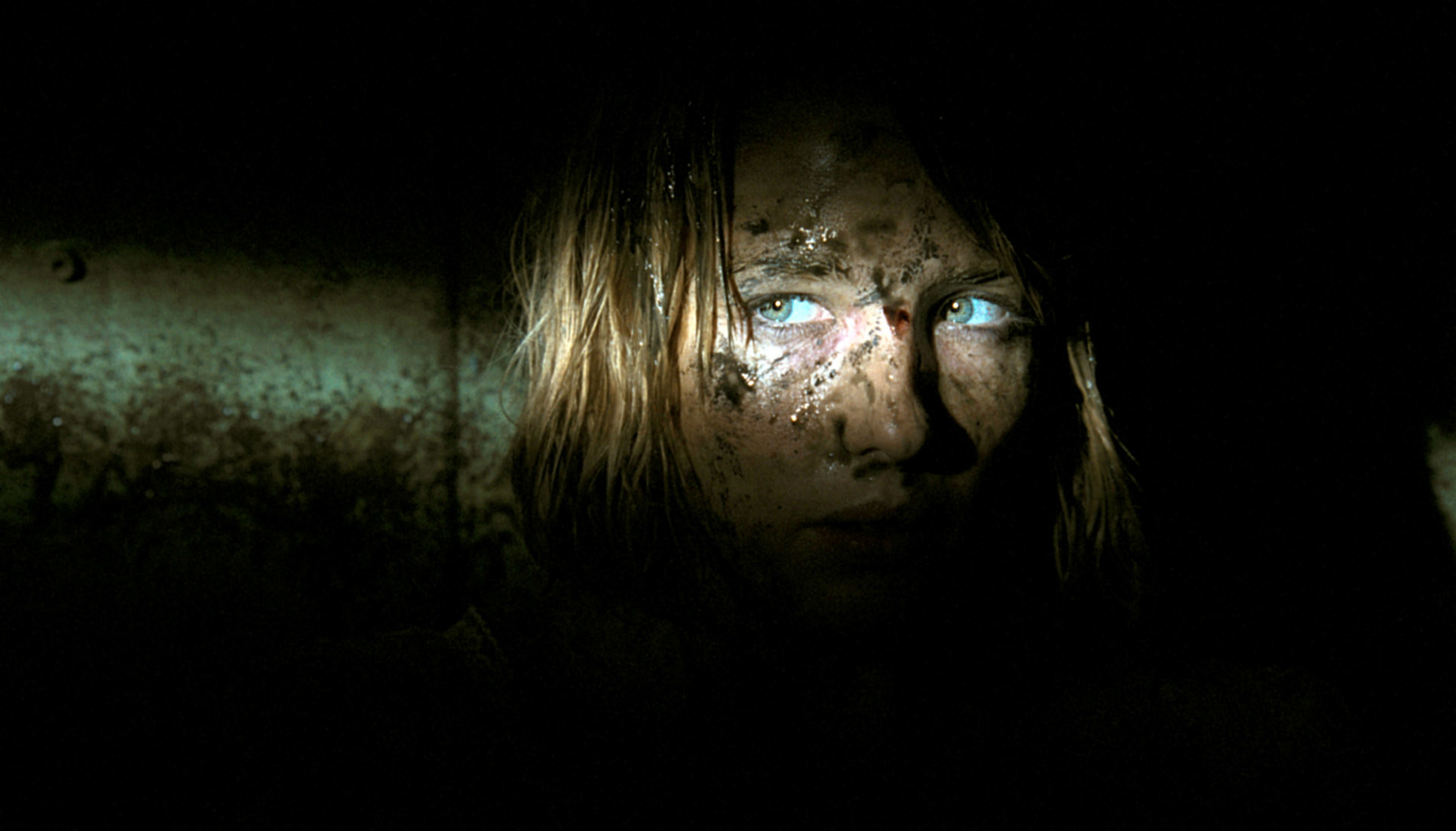 light shining on a woman&#x27;s eyes, face covered in mud