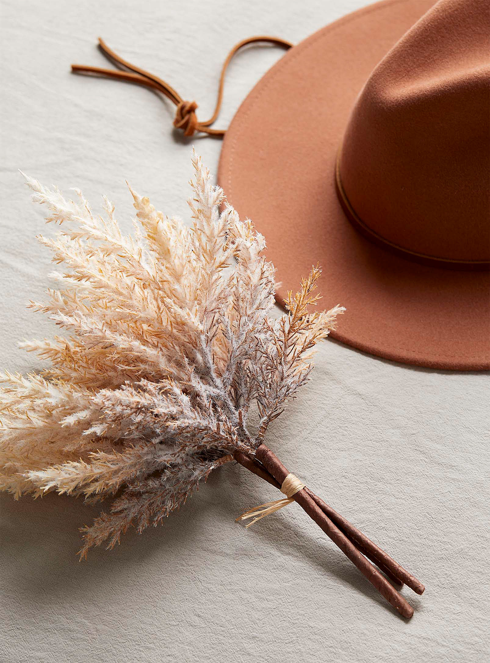 a bouquet of faux reed flowers next to a hat
