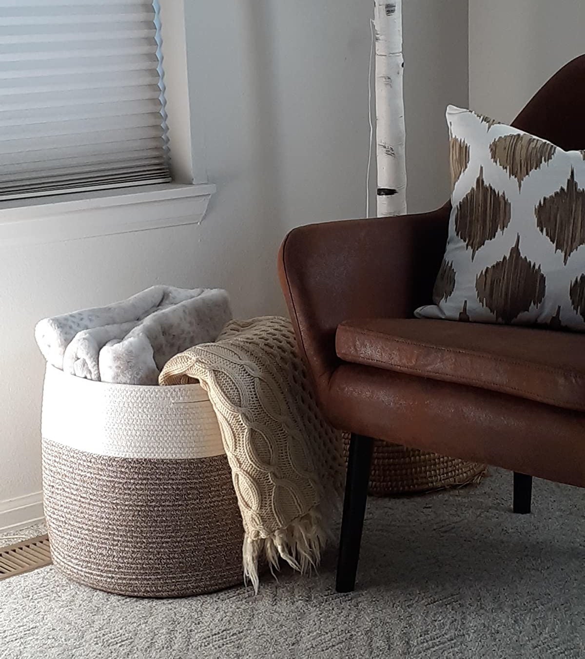the &quot;mele&quot; colored cotton basket holding several blankets on the floor of a reviewer&#x27;s living room