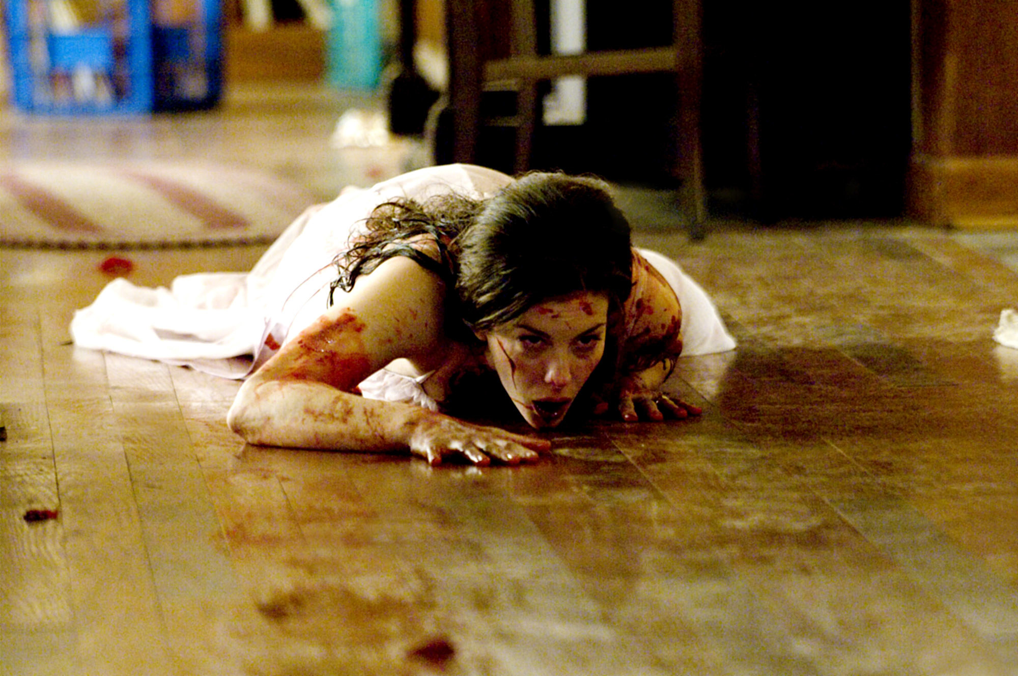 A bloodied woman crawls on the floor