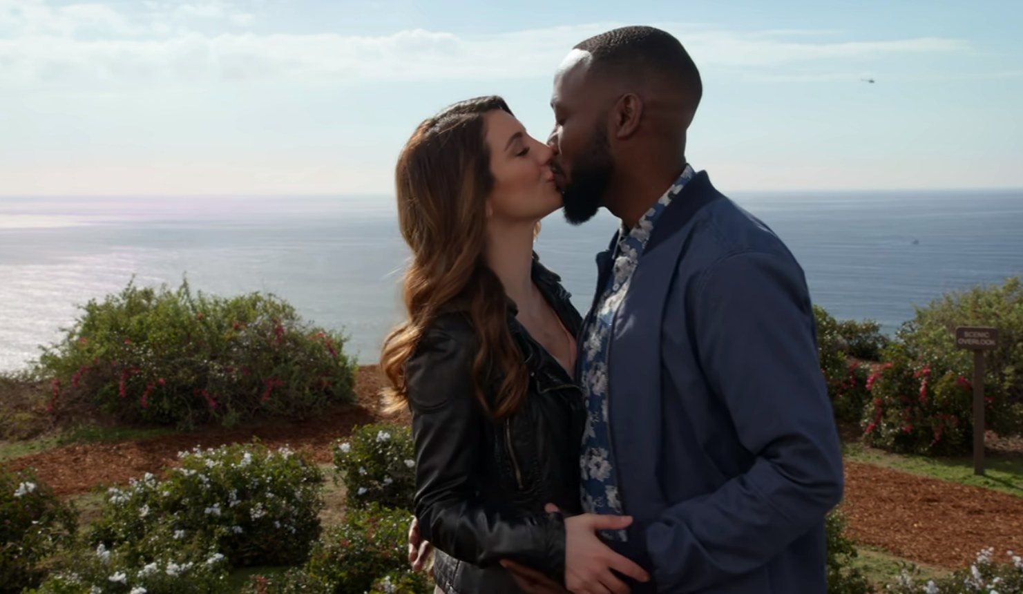 Aly and Winston kissing with the ocean in the background