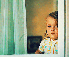 Little blonde girl staring out the window, all alone