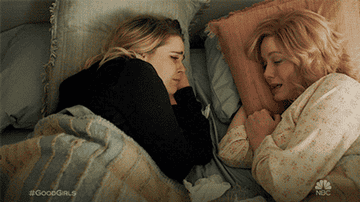 Scene from Good Girls, two sisters crying and holding hands in bed