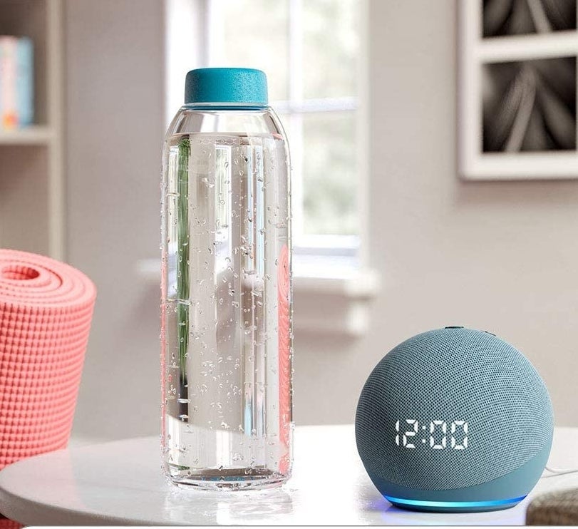 the echo dot next to a water bottle on a counter