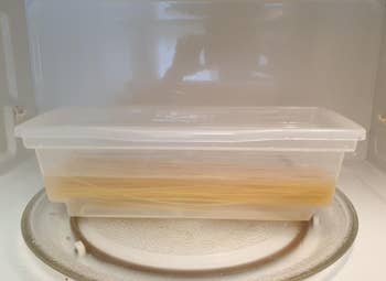 The pasta cooker filled with pasta and water inside of the microwave, ready to cook pasta