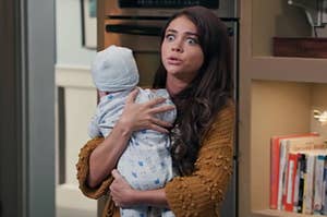 Sarah Hyland opening her eyes wide while holding a baby as Haley in Modern Family