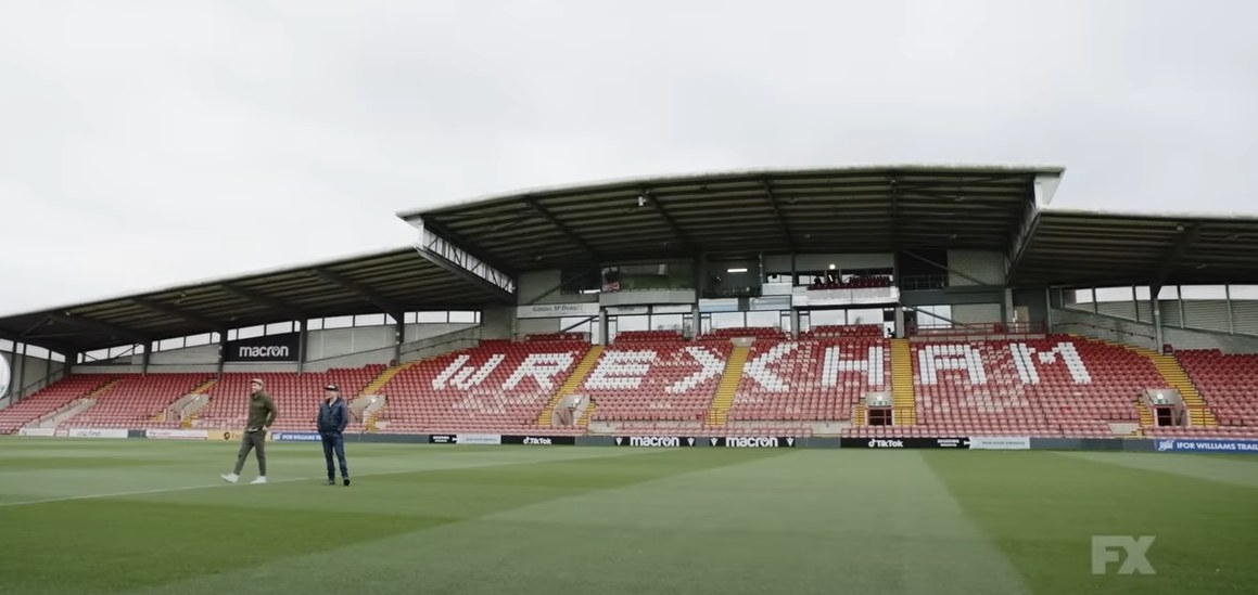 Ryan Ryenolds and Rob McElhenney standing on the field of the Wrexham stadium